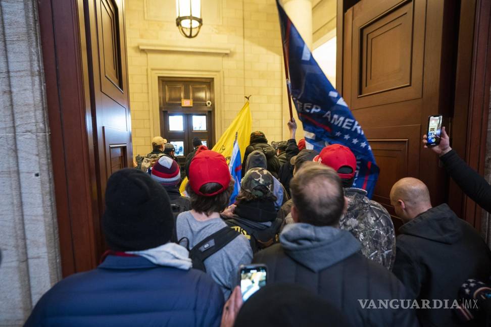 $!Partidarios del ex presidente Trump, están junto a la puerta del frente oriental después de violar la seguridad del Capitolio. EFE/EPA/Jim Lo Scalzo
