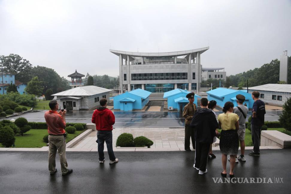 $!Turistas miran hacia un edificio de Corea del Sur mientras los soldados norcoreanos custodian la aldea de Panmunjom en la Zona Desmilitarizada.