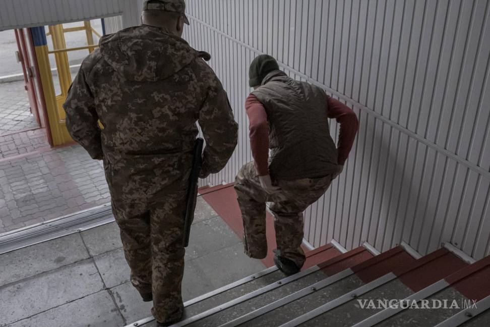 $!Un soldado de Wagner capturado es escoltado por un guardia ucraniano en una prisión en Dnipro.