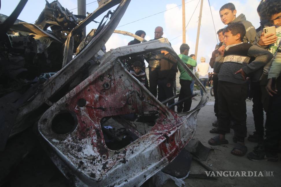 $!Menores palestinos observan un auto policial de Hamas destruido por un ataque israelí, en Rafah.