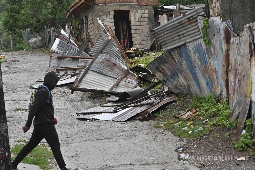 $!Una persona camina frente a una casa afectada por el paso del huracán Melissa en Kingston, Jamaica.