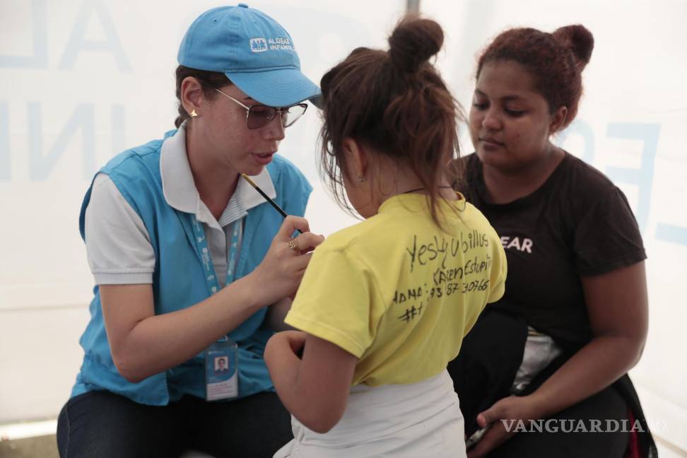 $!Una funcionaria de Aldeas Infantiles pinta la mano de una niña el 8 de julio de 2024 en Turbo (Colombia).
