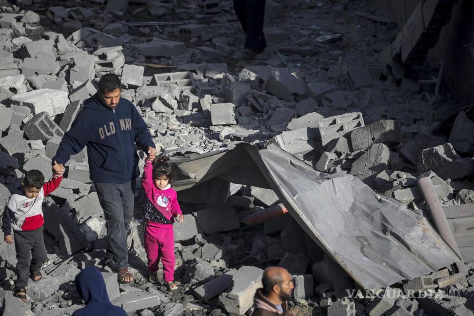 $!Un palestino con dos niños camina entre los escombros de una casa destruida tras los ataques aéreos israelíes en el campo de refugiados de Al Nusairat.