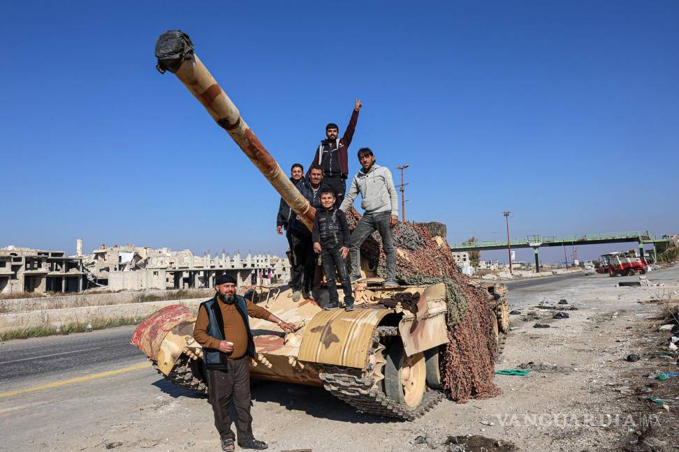 $!Un grupo de sirios se encuentran en la parte trasera de un tanque en la Autopista Internacional Alepo-Damasco M5, capturada por la oposición siria, Siria.