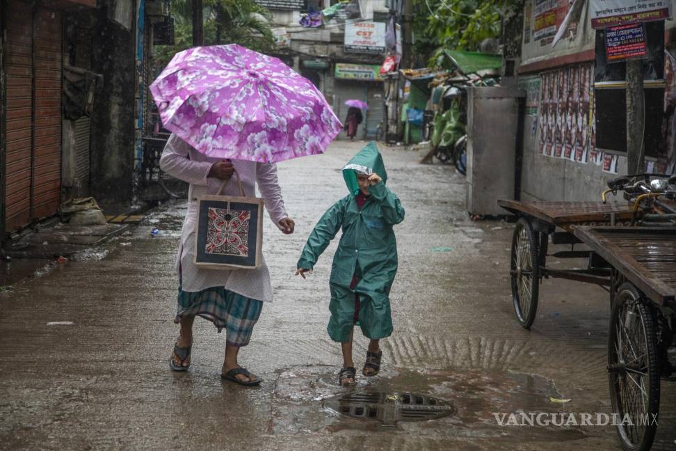 $!La gente camina por la calle durante las fuertes lluvias mientras el ciclón Midili afecta la zona costera de Dhaka, Bangladesh.