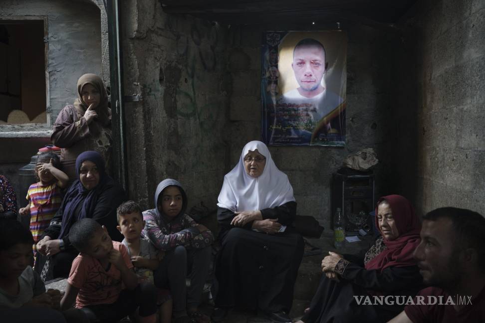 $!Miembros de la familia Nassir se sientan bajo un cartel con la imagen de Mohamed Nassir, que murió en la reciente guerra de 11 días entre Israel y Hamas, el grupo armado que controla Gaza, el sábado 12 de junio de 2021 en Beit Hanoun, en el norte de la Franja de Gaza. AP/Felipe Dana