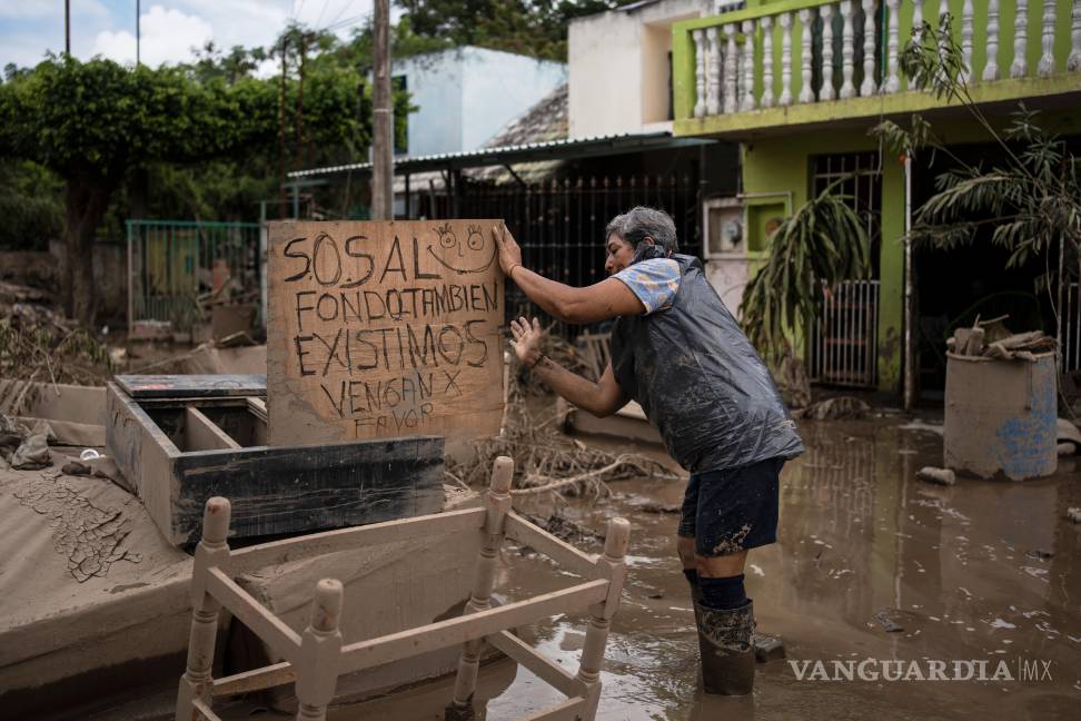 $!Una mujer alza un cartel que dice “SOS. En el fondo también existimos. Por favor, vengan”, en Poza Rica, Veracruz, México las tras inundaciones.