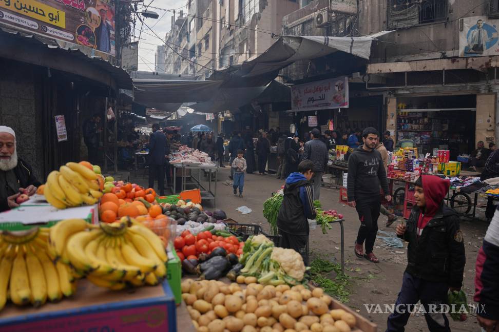 $!Palestinos caminan por un mercado callejero donde se venden frutas y verduras en la ciudad de Gaza.