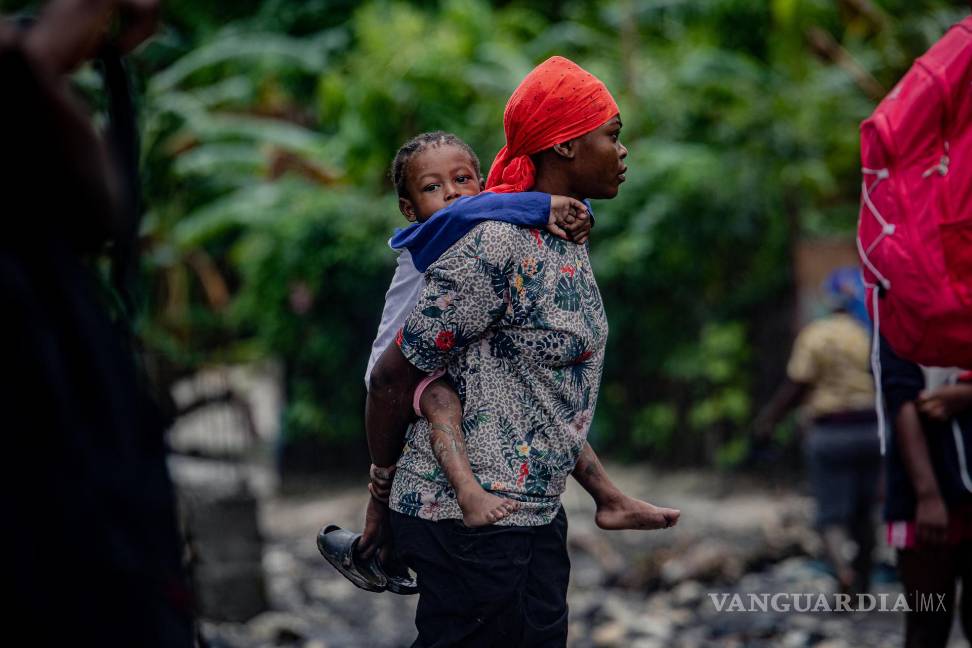 $!Una mujer lleva cargada una niña tras el paso del huracán Melissa en Petit-Goâve, Haití.