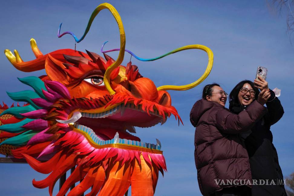 $!Dos mujeres se toman un selfie delante de una linterna gigante con forma de dragón en el lago Houhai, en Beijing.