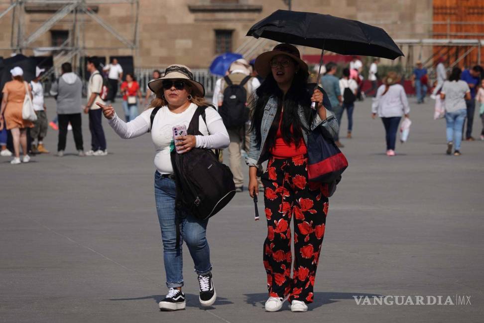 $!Mujeres se cubren de los fuertes rayos del sol debido a la ola de calor que se presenta en la capital.