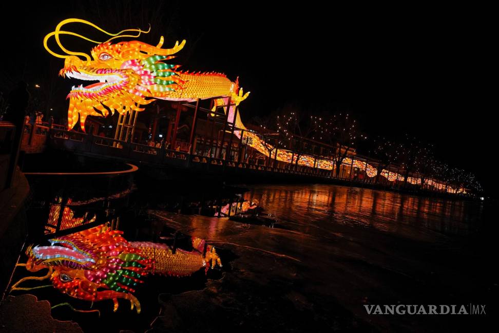 $!Visitantes pasan por debajo de una linterna enorme con forma de dragón, en el lago Houhai, en Beijing.