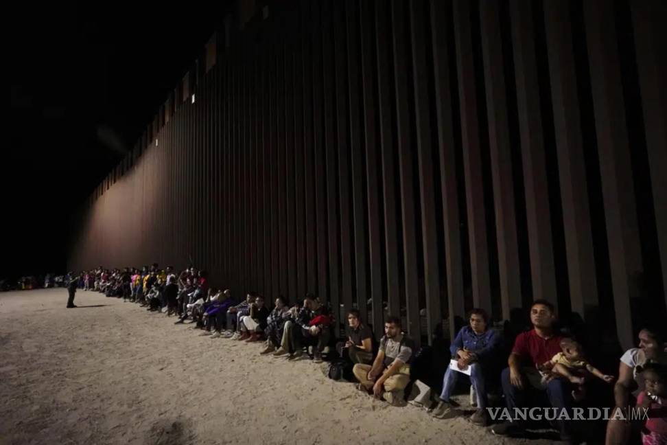 $!Migrantes esperan a lo largo de un muro fronterizo el 23 de agosto de 2022, después de cruzar desde México cerca de Yuma, Arizona.