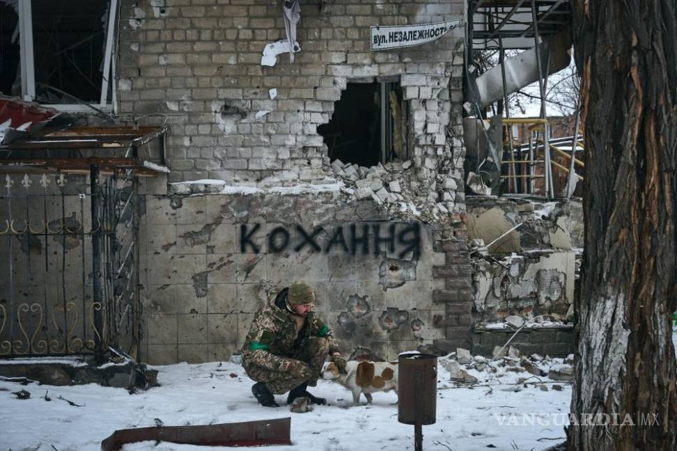 $!Un soldado ucraniano acaricia a un perro en Bakhmut, Ucrania. El letrero en la pared dice “Amor”, el letrero de la calle dice “Calle de la Independencia”.
