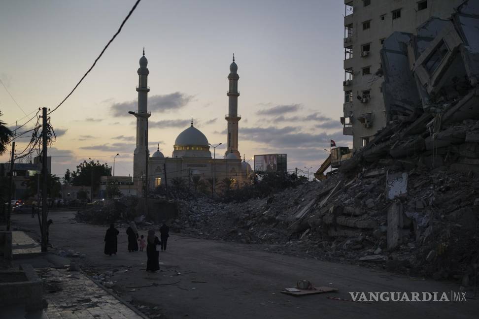$!Palestinos caminan junto a los escombros de un edificio destruido por un ataque aéreo en la guerra de 11 días entre Israel y Hamas, el grupo armado que controla Gaza, en Ciudad de Gaza, el jueves 10 de junio de 2021. AP/Felipe Dana