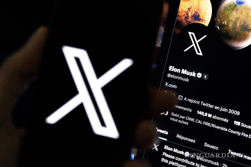 $!Una imagen ilustrativa muestra a un usuario sosteniendo un teléfono móvil que muestra el logotipo ‘X’ frente a la página de Elon Musk en Los Ángeles, California.
