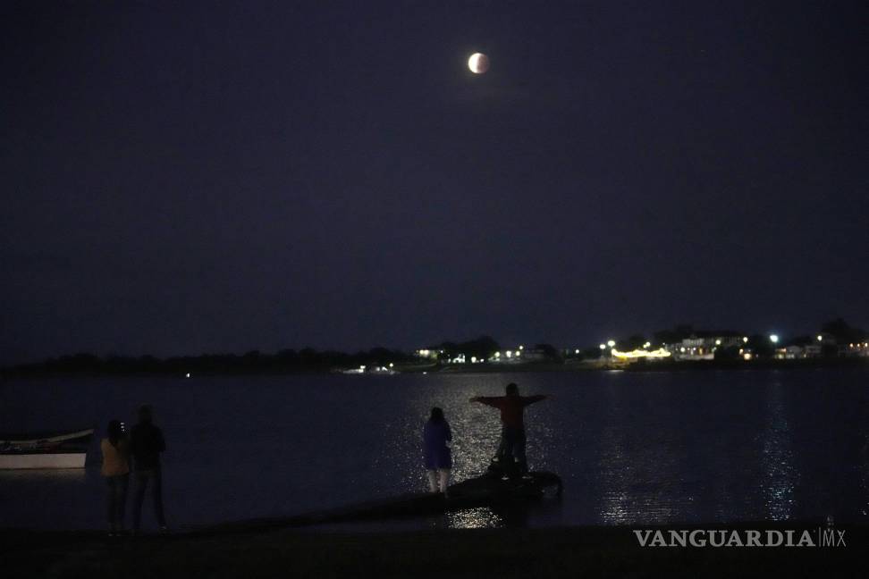 $!La gente se reúne para ver la luna parcialmente eclipsada que se asienta sobre el río Paraguay en Asunción, Paraguay. AP/Jorge Saenz