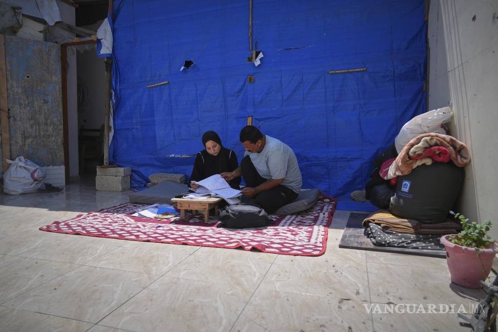 $!Sarah Qanan estudia con su padre, Ibrahim, en la tienda de campaña de su familia en Khan Younis, Franja de Gaza.