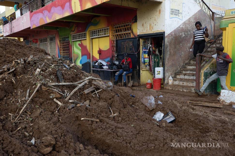 $!Personas caminan por el lodo en una calle afectada por el paso del huracán Melissa en Santa Cruz, Jamaica.