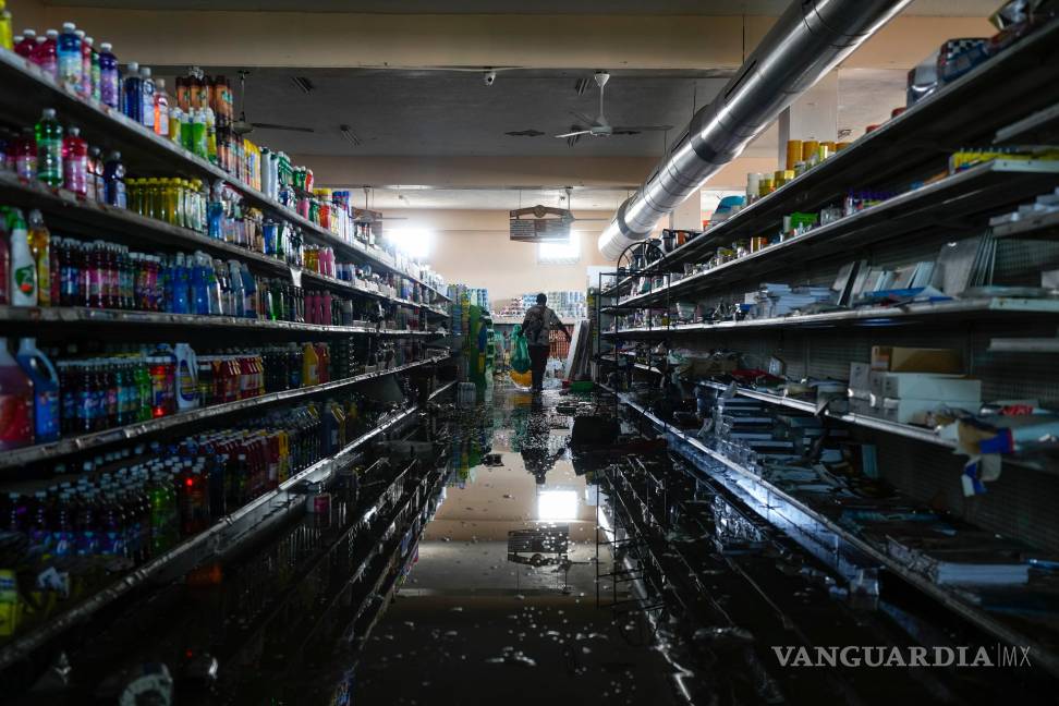 $!Con el permiso del dueño del supermercado, un residente se sirve provisiones y alimentos en Black River, Jamaica tras el paso del huracán Melissa.