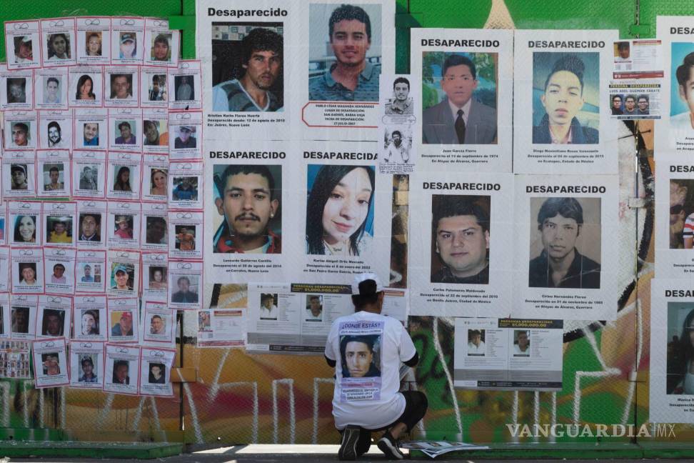 $!Una persona mira fotos de personas en la Glorieta de las y los Desaparecidos en CDMX.