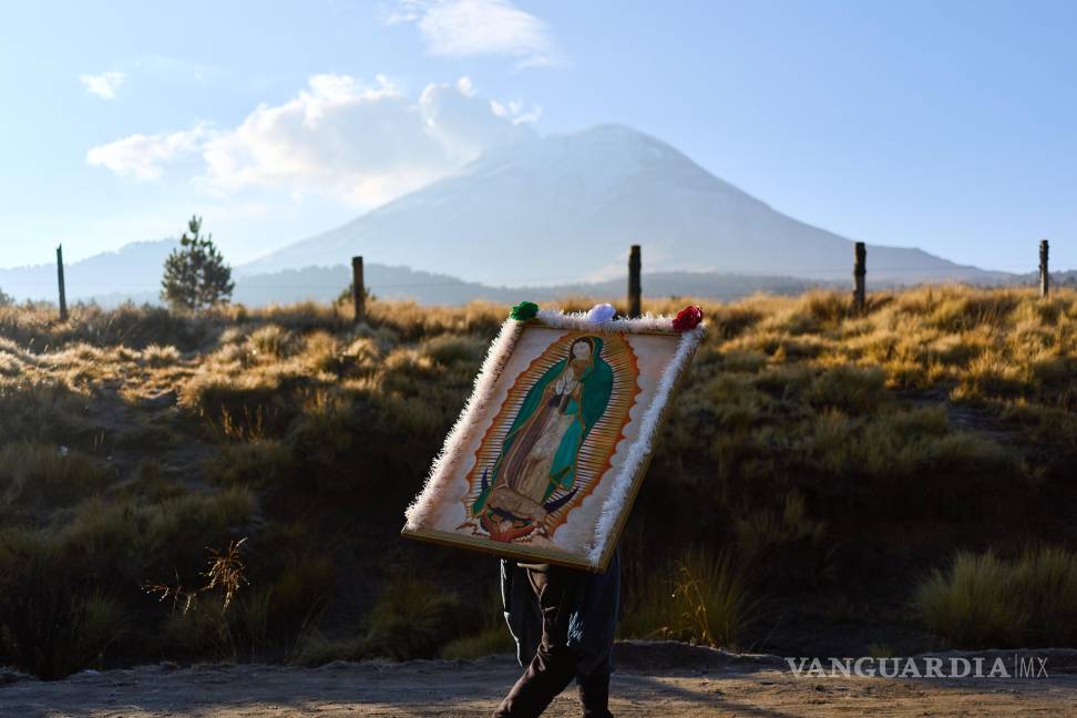 $!Un peregrino, que carga con una imagen de la Virgen de Guadalupe, pasa caminando por delante del Popocatepetl, en Paso de Cortés, de camino a CDMX.