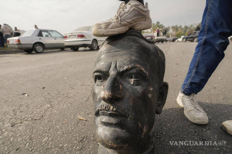 $!Un combatiente de oposición pone su pie sobre el busto del difunto presidente sirio Hafez Assad en Damasco, Siria.