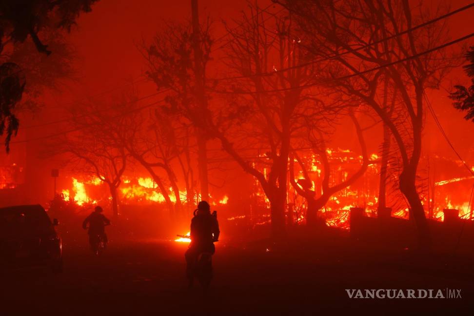 $!Dos personas pasan en motocicletas mientras el incendio de Palisades destruye un vecindario en el vecindario Pacific Palisades de Los Ángeles.