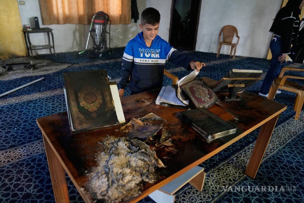 $!Un niño inspecciona copias quemadas del Corán dentro de una mezquita que fue incendiada y profanada por colonos israelíes en la ciudad de Deir Istiya.