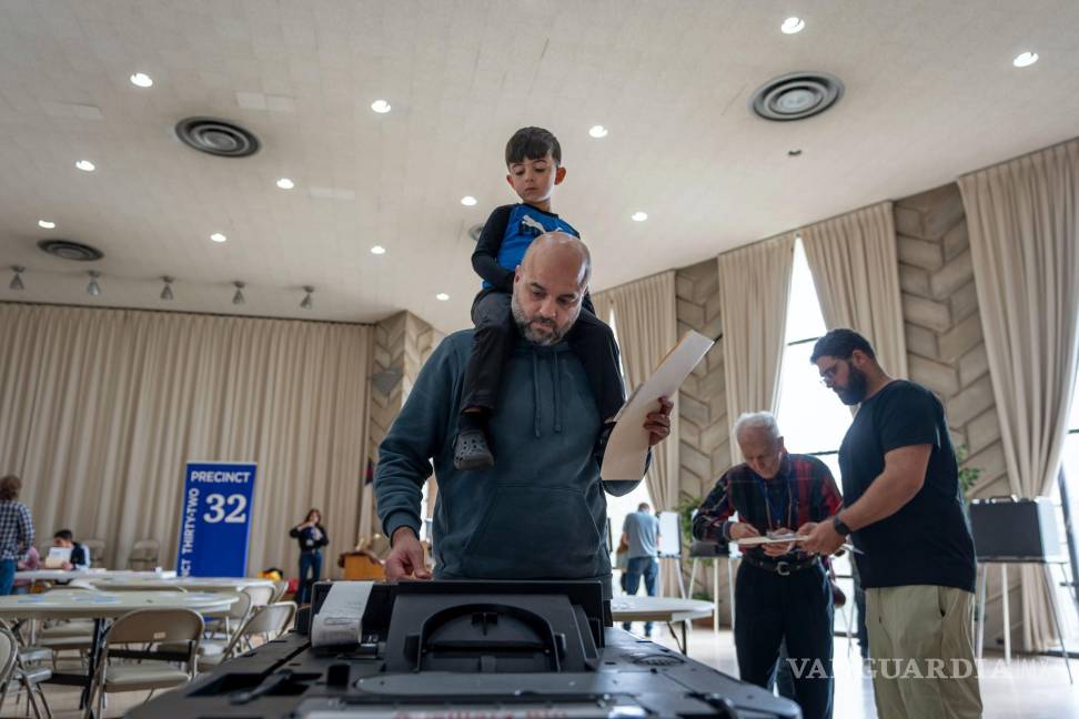 $!Three-year-old Zayn, sits on his father's shoulders as he inserts his ballot into a machine to vote at the First Presbyterian Church of Dearborn, on Election Day, Tuesday, Nov. 5, 2024, in Dearborn, Mich. (AP Photo/David Goldman)