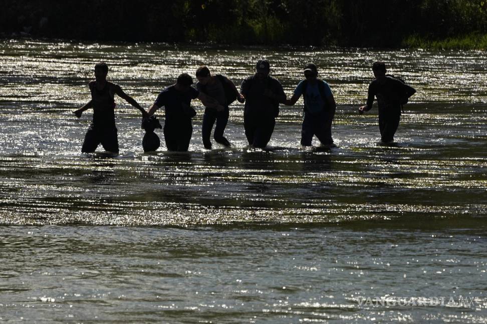 $!Migrantes se toman de las manos mientras cruzan el Río Grande.