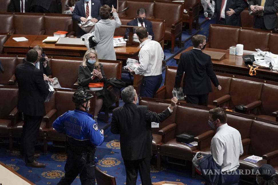 $!Miembros de la Cámara de Representantes abandonan el recinto mientras los manifestantes intentan irrumpir en el Capitolio. AP/J. Scott Applewhite