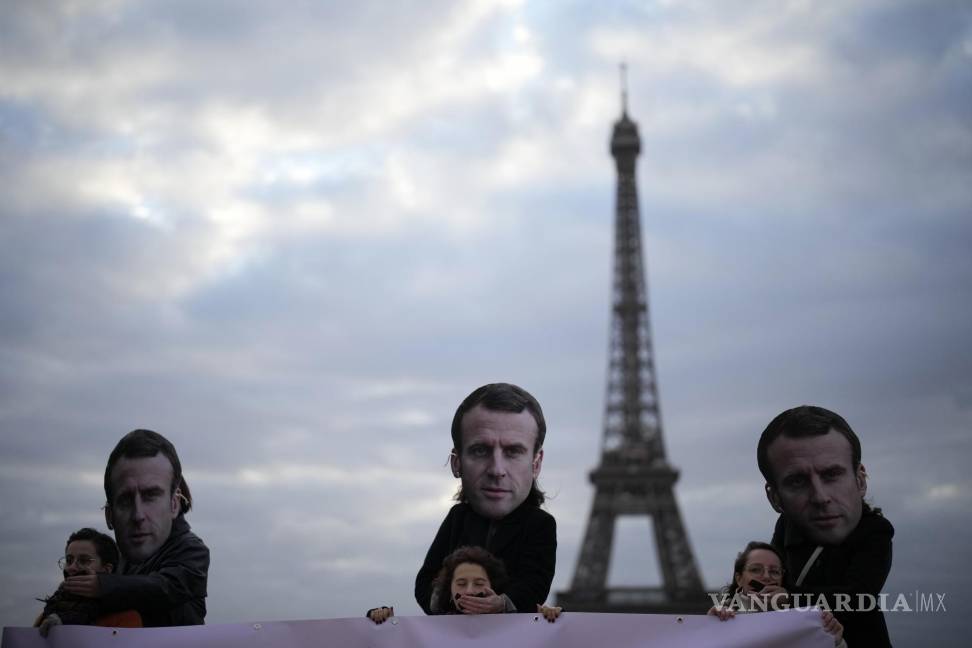$!Personas con máscaras del presidente francés Emmanuel Macron protestan en París.