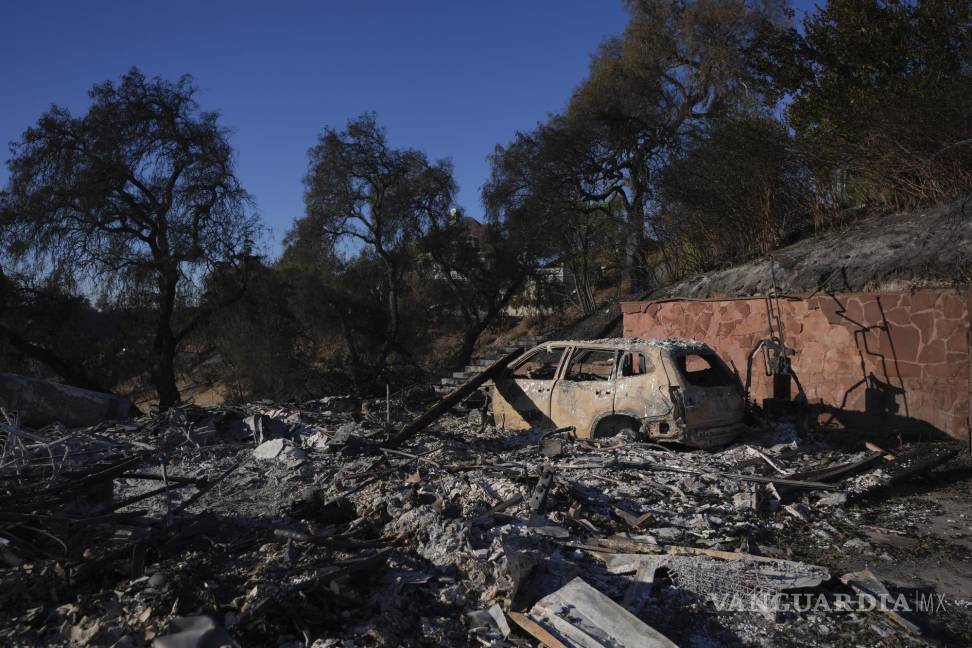 $!Los restos de un automóvil yacen en el lugar de una casa destruida por el incendio Mountain en Camarillo, California.