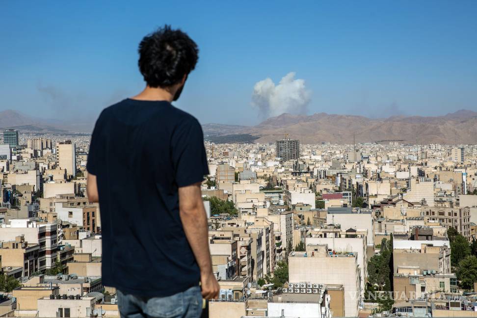 $!Un hombre en Teherán observa cómo se elevan columnas de humo durante un ataque aéreo israelí.