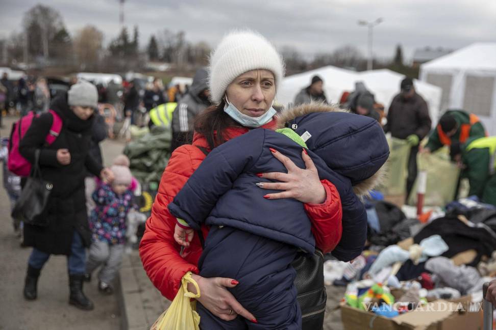 $!Una mujer carga a su hijo a su llegada al cruce fronterizo de Medyka tras huir de Ucrania, en Polonia, el lunes 28 de febrero de 2022.