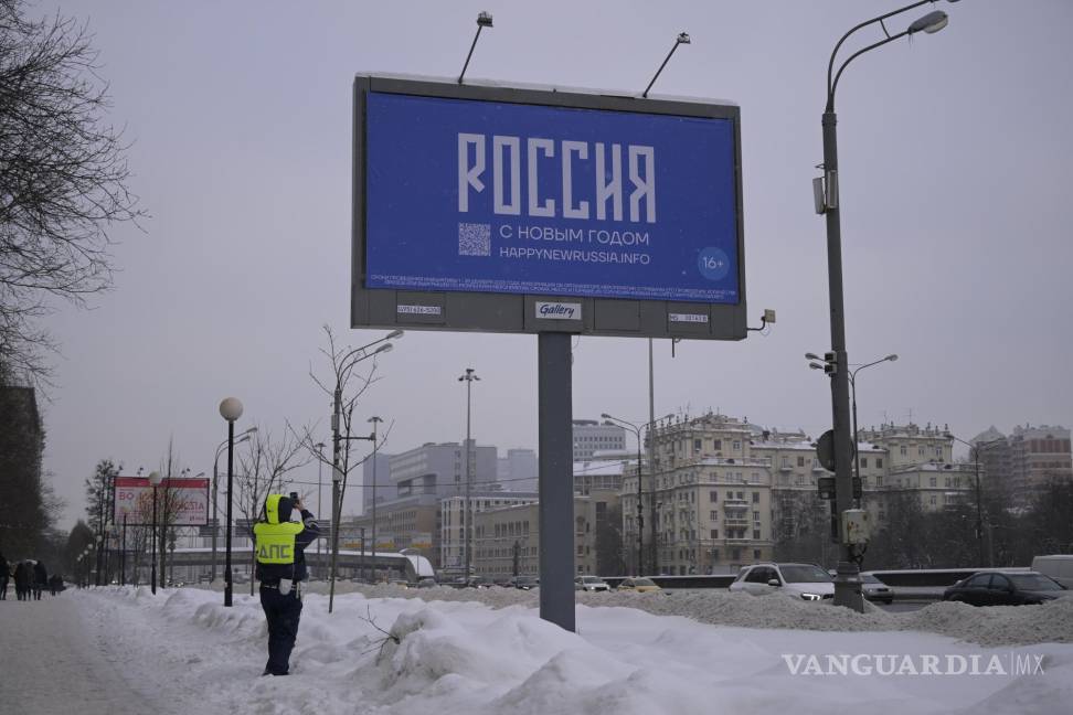 $!Un oficial de la policía de tránsito toma una fotografía de un cartel con las palabras Feliz Año Nuevo y el código QR en Moscú, Rusia.