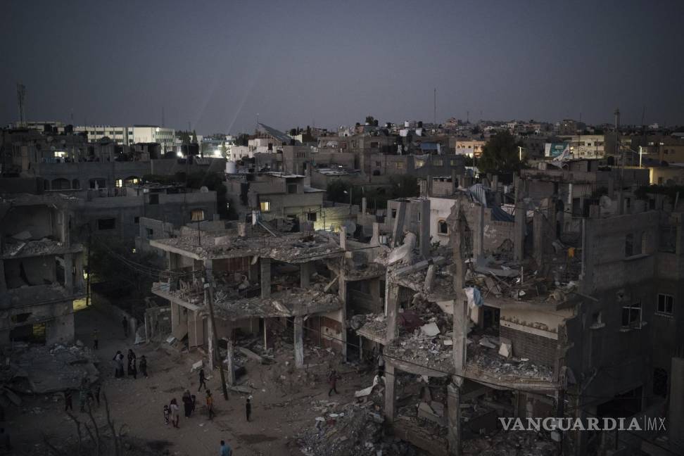 $!Palestinos caminando por la noche en la calle Al-Baali, cerca de casas dañadas por los ataques aéreos en la guerra de 11 días entre Israel y Hamas, el grupo que controla Gaza, en Beit Hanoun, en el norte de la Franja de Gaza, el lunes 31 de mayo de 2021. AP/Felipe Dana