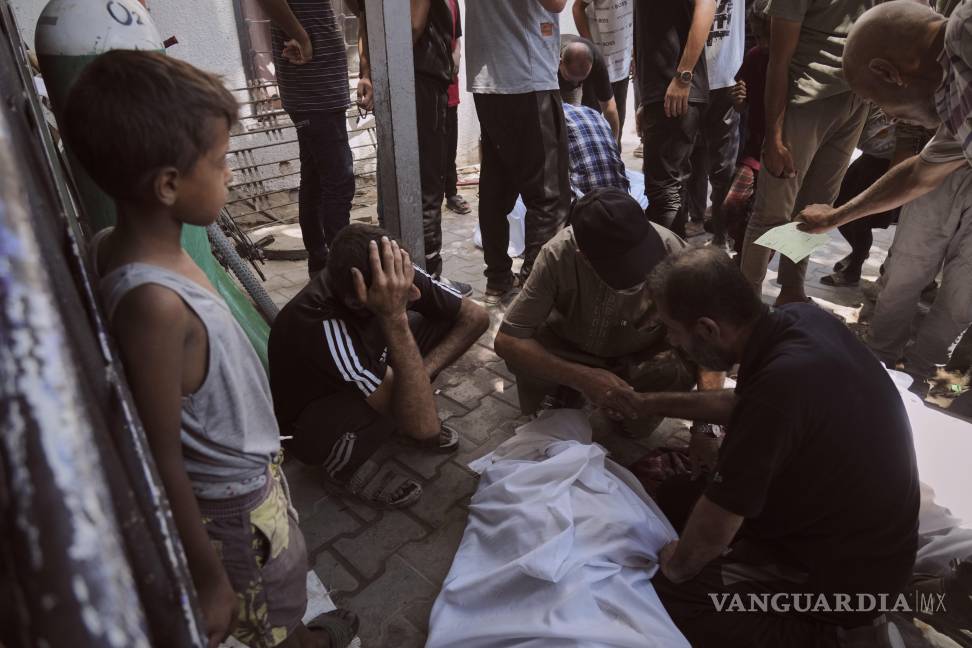 $!Dolientes se reúnen en torno a los cadáveres de los palestinos que murieron al intentar llegar a los camiones de ayuda que ingresan al norte de Gaza.