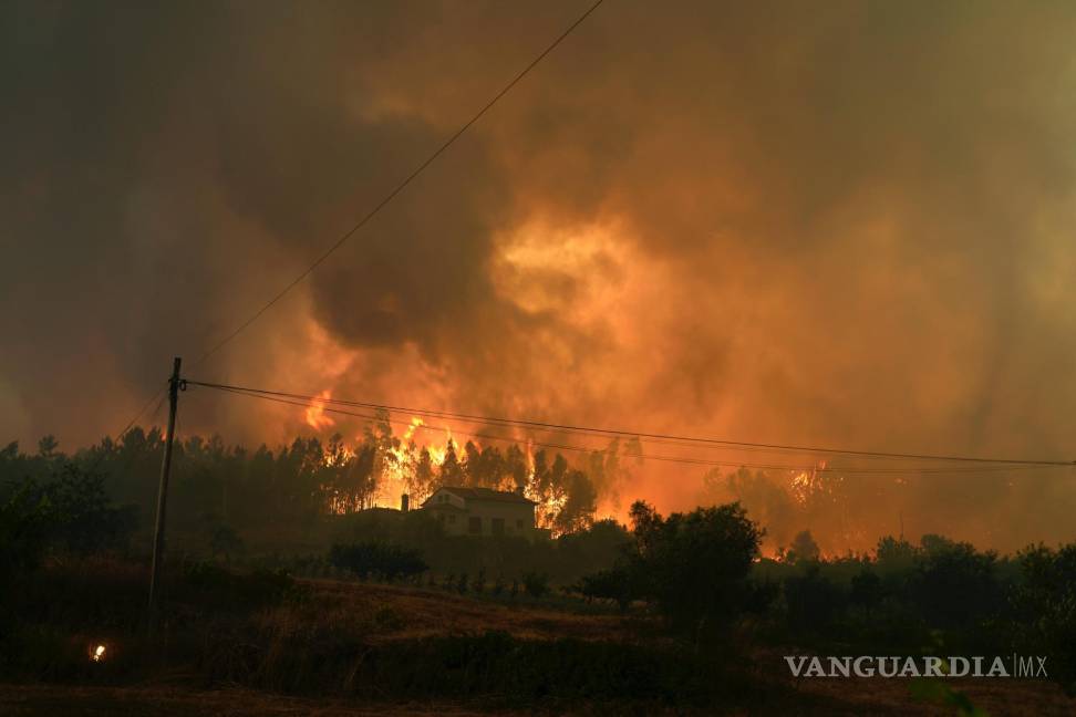 $!Un incendio forestal se cierra en una casa en el pueblo de Bemposta, cerca de Ansiao, en el centro de Portugal.