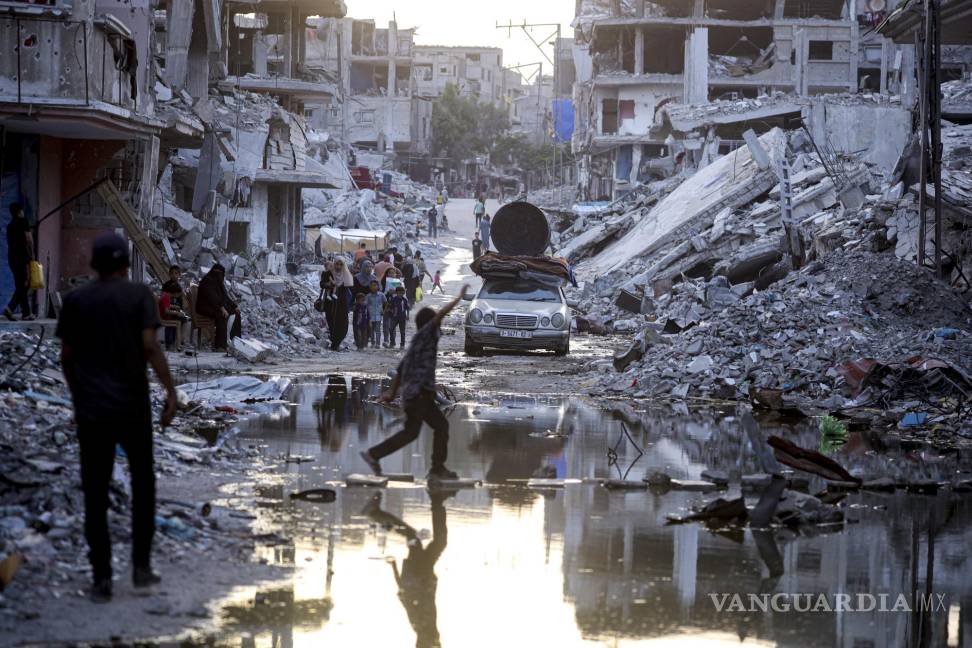 $!Palestinos desplazados por la ofensiva terrestre y aérea de Israel en la Franja de Gaza caminan cerca de aguas residuales en las calles del poblado de Jan Yunis.