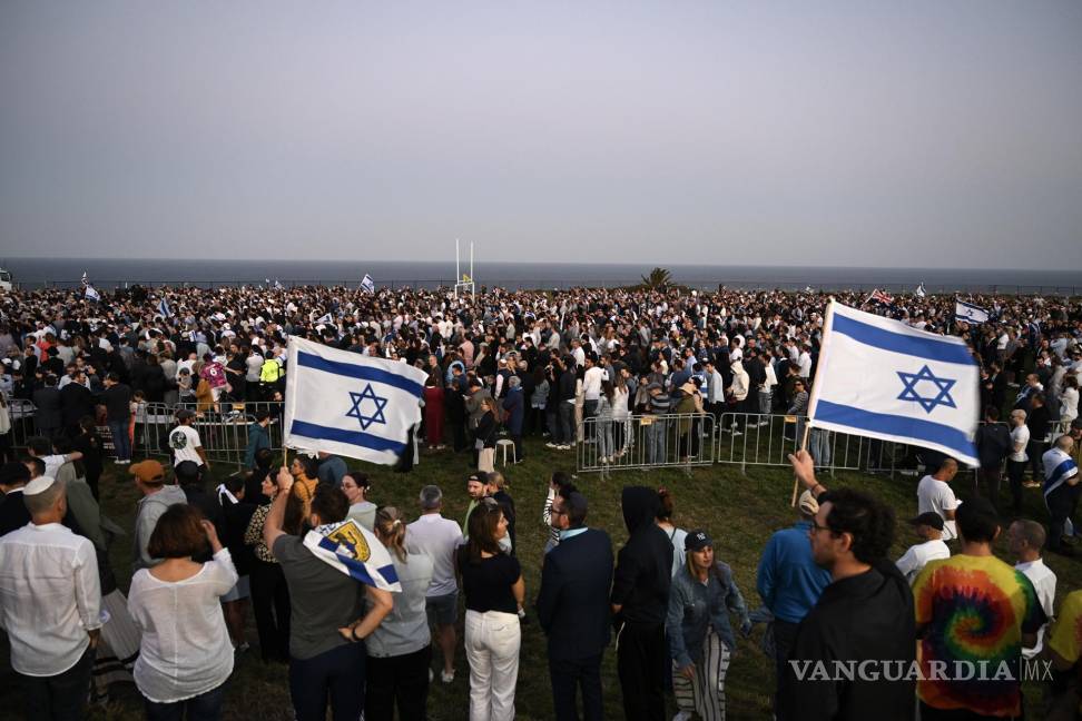 $!Personas con banderas israelíes en una vigilia organizada por la comunidad judía de Sydney en Dover Heights, al este de Sydney.