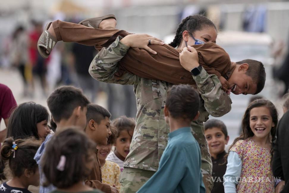 $!Un soldado estadounidense juega con niños afganos recientemente evacuados en la base aérea estadounidense de Ramstein, Alemania. La comunidad militar estadounidense más grande en el extranjero alberga a miles de refugiados afganos en una ciudad de tiendas de campaña cada vez más concurrida. AP/Matthias Schrader