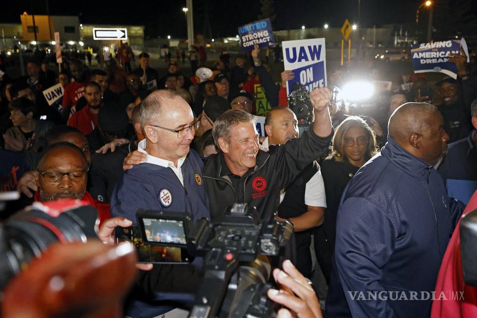$!El presidente del sindicato UAW, Shawn Fain (i), celebra junto al vicepresidente, Chuck Browning (c), frente a la fábrica Ford Michigan Assembly en Wayne.