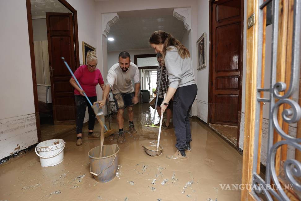 $!Varias personas limpian el lodo acumulado en el interior de su vivienda a causa de las intensas lluvias por la fuerte DANA en Valencia.