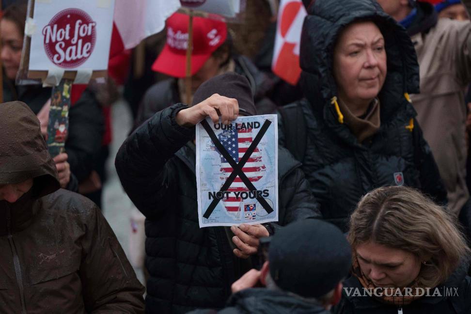 $!Un hombre sostiene un mapa de Groenlandia cubierto con la bandera de EU tachada con una X en una protesta contra la política de Trump en Nuuk.