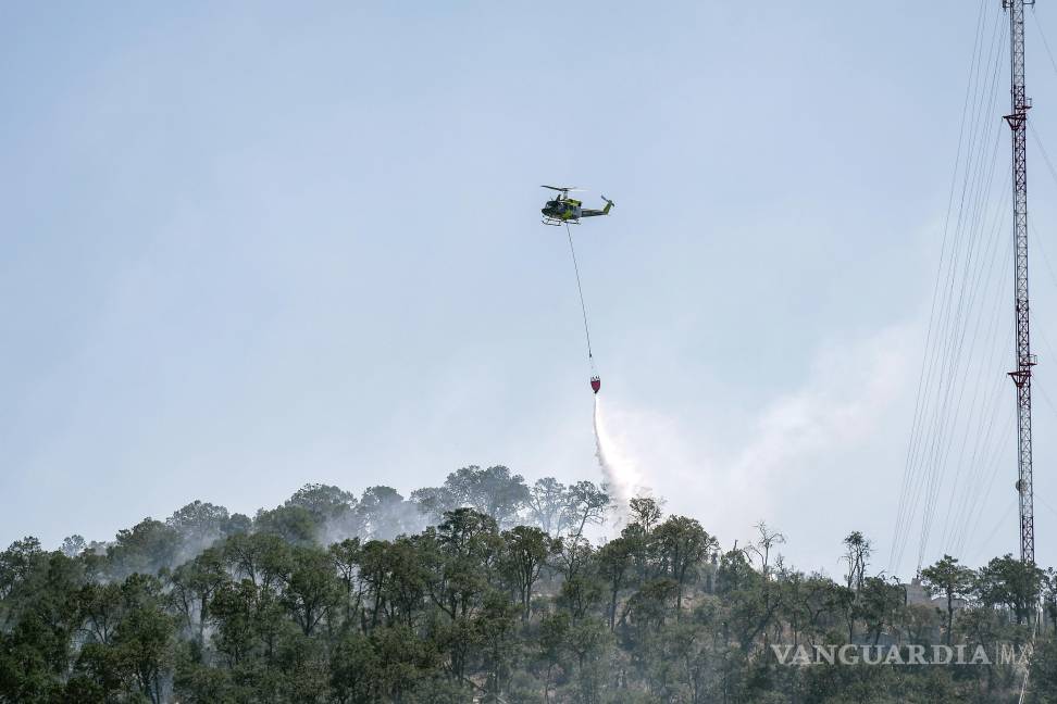 $!Un helicóptero Bell 212 realizando descargas de agua sobre las áreas afectadas por el incendio en El Tunal, para frenar su avance.