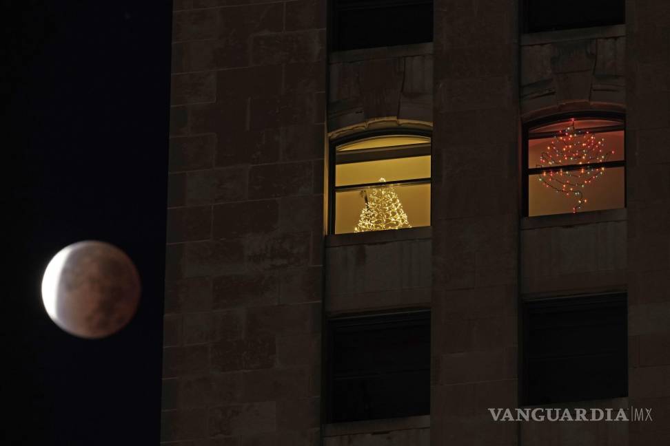 $!La sombra de la tierra cubre la luna llena durante un eclipse lunar parcial cuando se pone más allá de un edificio de apartamentos en el centro de Kansas City, Missouri. AP/Charlie Riedel