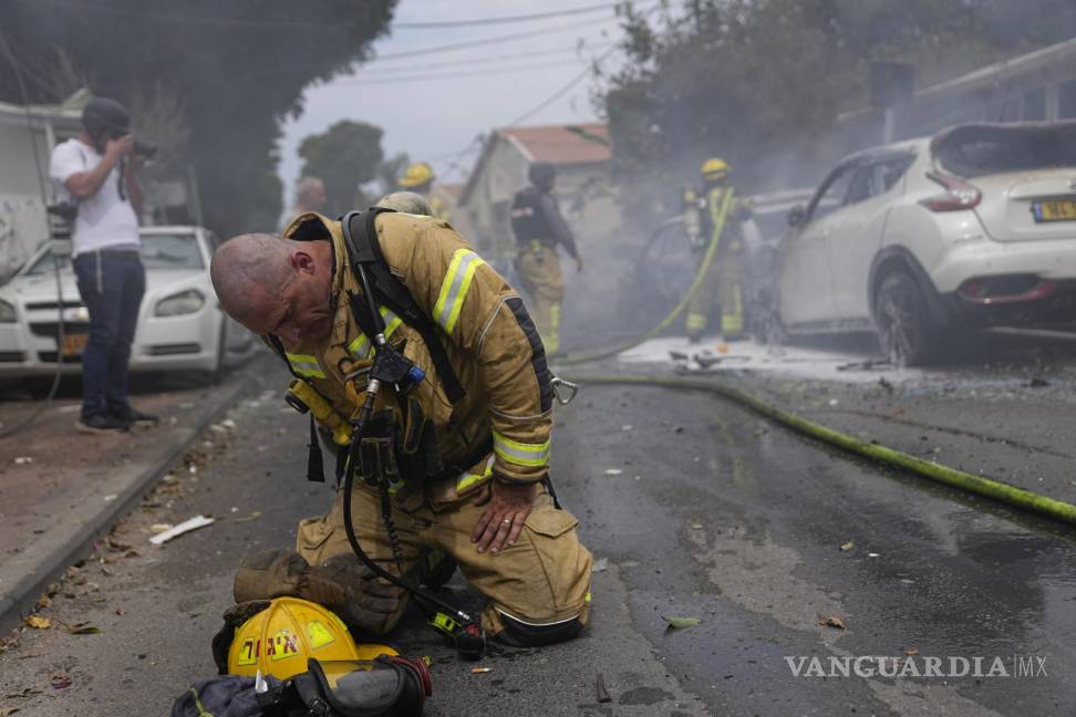 $!Un bombero israelí se arrodilla exhausto después de que él y sus compañeros apagaron vehículos incendiados por los cohetes lanzados desde la Franja de Gaza, el lunes 9 de octubre de 2023, en Ascalón, Israel. (AP Foto/Ohad Zwigenberg)