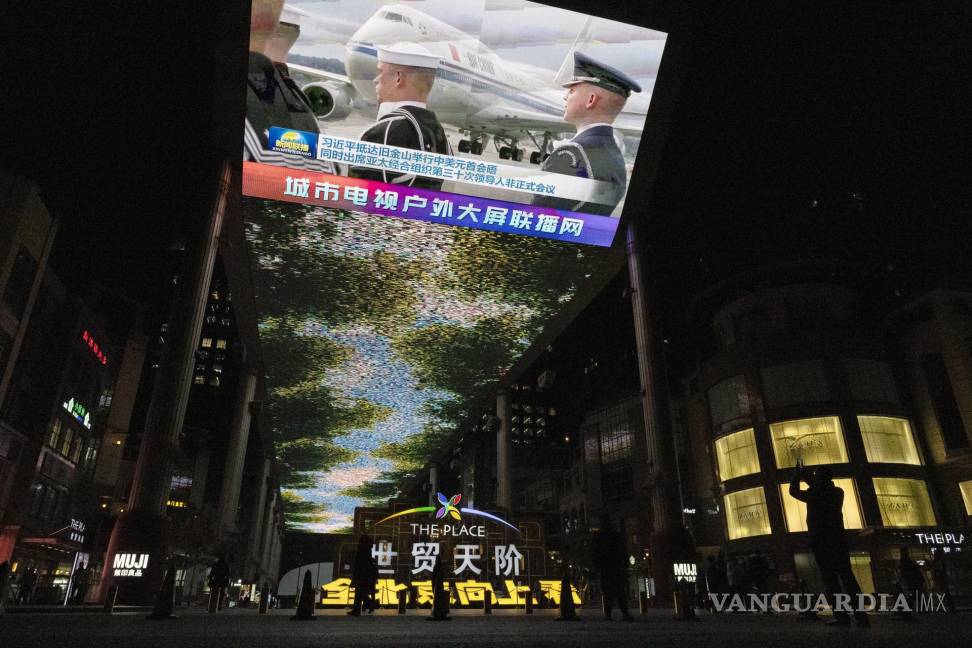 $!Un hombre (d) toma una fotografía de una gran pantalla que muestra la llegada del presidente chino Xi Jinping a Estados Unidos, en un centro comercial de Beijing.